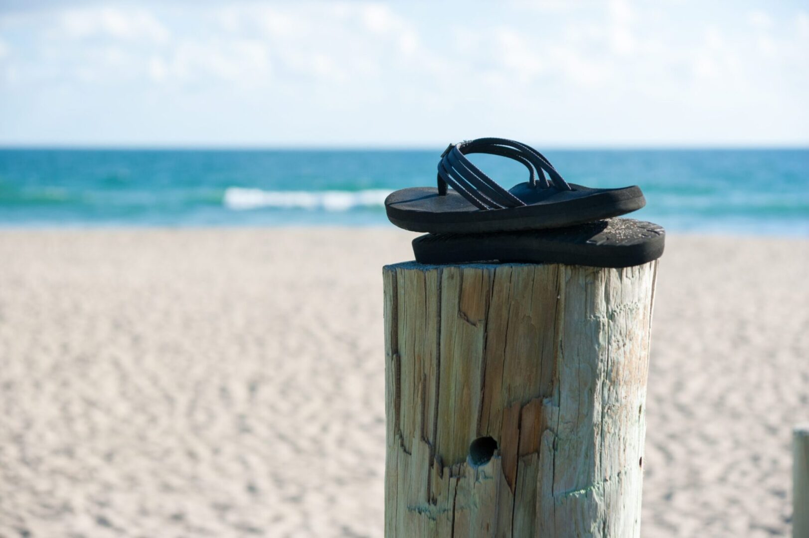 A pair of flip flops sitting on top of a wooden post.